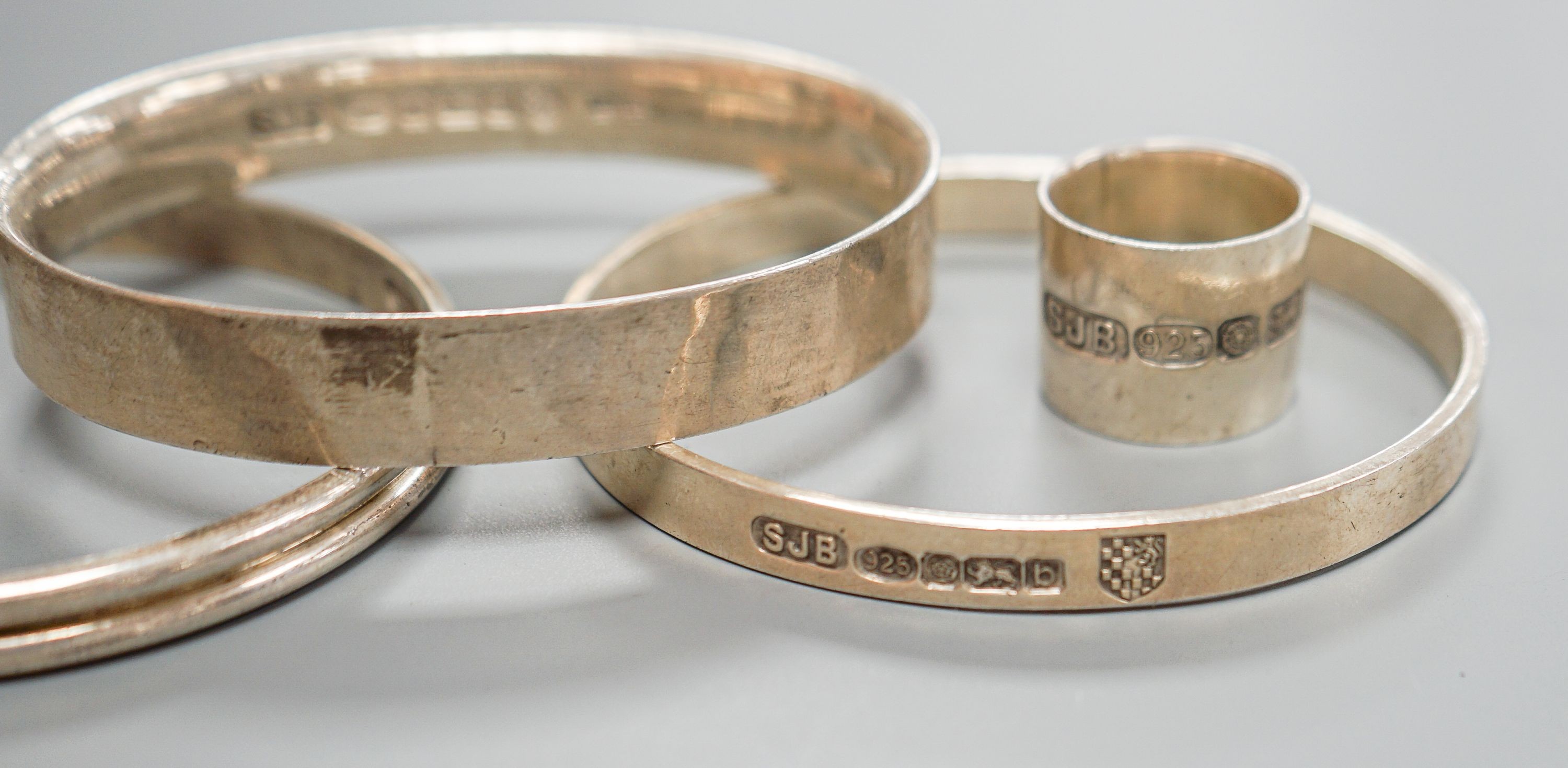 Three modern silver bangles and a large silver band, all by Simon J. Beer of Lewes